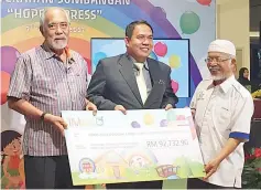  ??  ?? Megat Najmuddin (left) handing over a mock cheque to Safari, witnessed by a representa­tive from the State Welfare Department.