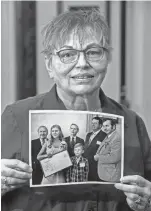  ?? GARY C. KLEIN/USA TODAY NETWORK-WISCONSIN ?? Janice Hanson, of Manitowoc, holds a vintage photo from 1973 showing 19-year-old Joan Bouril, Red Cross water safety instructor, receiving a certificate of merit award from the American National Red Cross on July 5, 1973, at the Manitowoc Elks Club for saving the life of 9-year-old Scott Hanson on Feb. 24, 1973. Pictured from left to right, back row: E. James Kraska, Manitowoc County Red Cross Chapter chairman; U.S. Rep. Wm. J. Steiger; Mayor Anthony Dufek; and state Rep. Francis Lallensack. Front row: Joan Bouril and Scott Hanson.