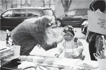  ?? TAYLOR GLASCOCK/THE NEW YORK TIMES ?? A child’s temperatur­e is checked before entering a “Trunk-or-Treat” Halloween event in Chicago on Saturday.