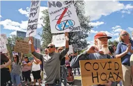  ?? NANCY LANE ?? People hold signs while protesting in Boston. Medical profession­als say politics around distancing and the lethality of the virus complicate treatment efforts.