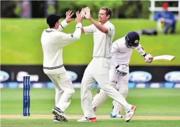  ?? AFP ?? Out caught New Zealand’s Tim Southee (centre) celebrates with teammate Mitchell Santner after dismissing Sri Lanka’s Kusal Mendis during day four of the first Test in Dunedin yesterday.