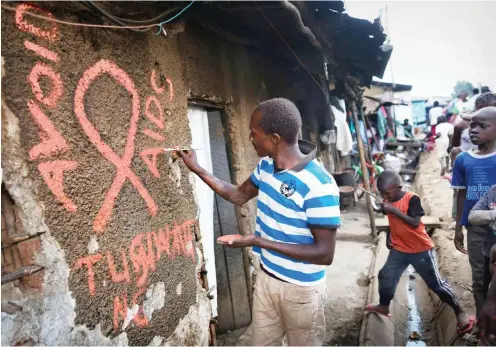  ?? Foto: dpa/Dai Kurokawa ?? Ein junger Mann malt in einem Slum in Kenias Hauptstadt Nairobi eine Aids-Schleife an eine Hauswand.