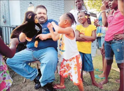  ?? Jim Weber/The Commercial Appeal ?? As part of his Citizens Police Academy voluntaris­m, formerly homeless Lee Brown, 40, attends a National Night Out at New Hope Ministries where “Chimmy the safety monkey” advises kids, including Quishawn Addison, 3, on emergency phone numbers and other...