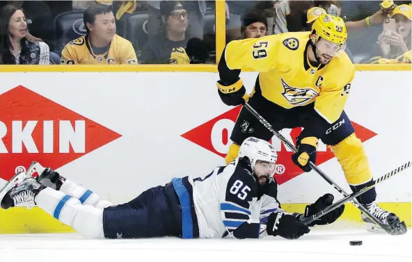  ?? — THE ASSOCIATED PRESS ?? Mathieu Perreault of the Winnipeg Jets and Roman Josi of the Nashville Predators compete for the puck in second-round playoff action Saturday night in Nashville, Tenn. Perreault’s return to Winnipeg’s lineup comes at a key time in a hard-fought series.