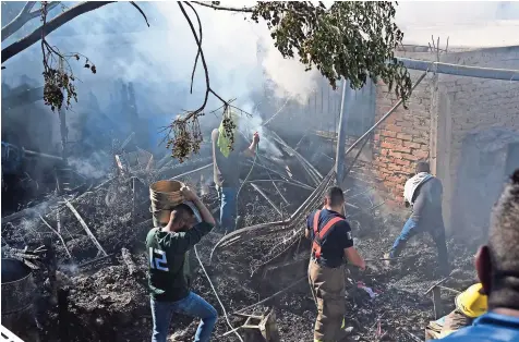  ??  ?? VECINOS ayudan a sofocar las llamas con cubetas de agua