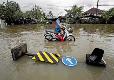  ?? AP ?? A man pushes a motorcycle through floodwater­s from Tropical Storm Pabuk in Pak Phanang, in Thailand’s southern province of Nakhon Si Thammarat. The storm has caused disruption during Thailand’s high tourist season.