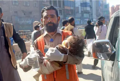  ?? AP ?? A volunteer carries child injured in Charsadda terror attack to a hospital in Peshawar on Tuesday. —