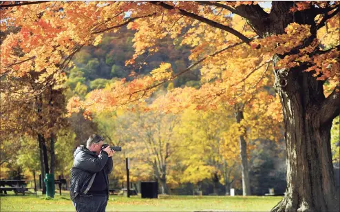  ?? Hearst Connecticu­t Media file photo ?? Dennis Mitchell of Sydney, Australia, stops at Squantz Pond in New Fairfield in 2016 to photograph the fall foliage around the state park. Longer summer droughts are likely to cause stress on New England trees, diminishin­g their vibrant fall colors, according to a new study.