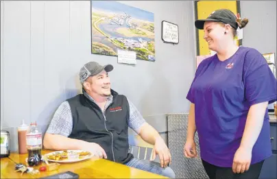  ?? MITCH MACDONALD/THE GUARDIAN ?? Tignish residents Sean McGivern, left, and April McInnis chat inside Shirley’s Café with an overhead picture of the town behind them. Both were surprised to hear of Tignish residents being turned away by a Charlottet­own hotel on New Year’s Eve because...