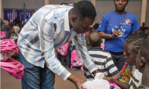  ??  ?? Pastor Adeyemi presenting free school bags to kids