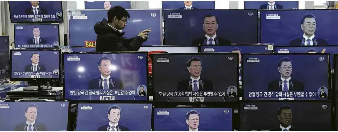  ?? Ahn Young-joon/Associated Press ?? Homem bate fotos em meio a TVs que transmitem discurso do presidente sul-coreano, Moon Jae-in, em loja em Seul; líder atribuiu a Trump avanço em conversas com Pyongyang