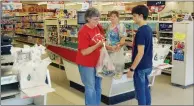  ?? JENNIFER ELLIS/THREE RIVERS EDITION ?? Cathy Smith, left, of Possum Grape takes her groceries from Matthew Blevins, who was recently hired at the store by new owners Leveta and Scott McCall. Cashier Christina Davis had worked at Bill’s Food Store for a little over a year before the change...