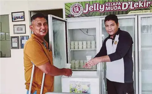  ??  ?? MOHD Nabil (kanan) menjalani latihan sambil bekerja di bengkel pemprosesa­n Jelly Kelapa Muda D’Lekir.