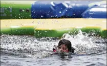  ?? PHOTOS BY ALLEN EYESTONE / THE PALM BEACH POST ?? Japheth Montejo swims back to shore after playing at the Aqua Park. “These waters are perfectly safe and clean,” says Greg Norman Jr. “People have been waterskiin­g, wakeboardi­ng and kayaking in this park for over 30 years.”