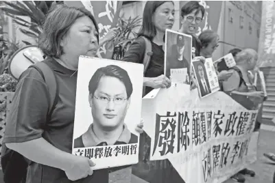  ?? — Gambar Reuters ?? PENUNJUK perasaan membawa gambar Lee (kiri) dan aktivis lain semasa mengadakan demonstras­i di Hong Kong, semalam.