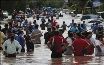  ?? AP PHOTO/DELMER MARTINEZ ?? Residents wade through a flooded road in the aftermath of Hurricane Eta in Planeta, Honduras, Thursday,. The storm that hit Nicaragua as a Category 4 hurricane on Tuesday had become more of a vast tropical rainstorm, but it was advancing so slowly and dumping so much rain that much of Central America remained on high alert.