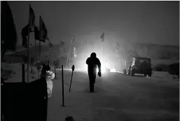  ?? Associated Press ?? n A camper walks through the Oceti Sakowin camp on Tuesday where people have gathered to protest the Dakota Access oil pipeline in Cannon Ball, N.D.