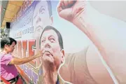  ?? AP ?? A resident checks damage on a tarpaulin billboard of leading presidenti­al candidate Mayor Rodrigo Duterte along a boulevard at his hometown in Davao city in the southern Philippine­s yesterday.