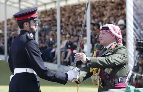  ?? Photos by Stephen Lock for The National ?? The UAE’s Ahmed Al Mazrui receives the internatio­nal sword from King Abdullah as recognitio­n for excellence after a year of training at Sandhurst