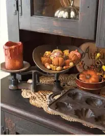  ??  ?? Above: In a cabinet in the breakfast area, petite pumpkins fill an antique bowl and a vintage scale. Julie and daughter Olivia made some of the small pumpkins from a mixture of cinnamon, applesauce and glue.