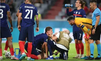  ?? Photograph: Matthias Hangst/Reuters ?? France’s Benjamin Pavard receives medical attention after sustaining a head injury.