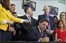  ?? Chris O’Meara/Associated Press ?? Florida Gov. Ron DeSantis, seated, signs a bill that protects employees and their families from coronaviru­s vaccine and mask mandates Thursday in Brandon, Fla.