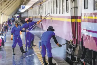  ?? Mladen Antonov / AFP via Getty Images ?? Workers disinfect a train at a Bangkok station. Authoritie­s are transporti­ng some people with coronaviru­s to their hometowns to alleviate the burden on the capital’s medical system.