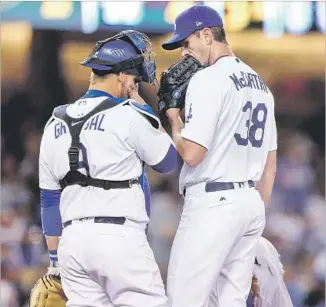  ?? Sean M. Haffey Getty Images ?? DODGERS CATCHER Yasmani Grandal and right-hander Brandon McCarthy talk during a game on April 17. McCarthy injured his left shoulder in the weight room last week.