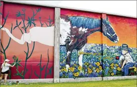  ?? DAVE MCDERMAND / COLLEGE STATION EAGLE ?? Muralist Tyler Kay Reichert (lower left) paints her panel for a series of murals on the side of the Conlee-Garrett Moving and Storage building in downtown Bryan on July 13.