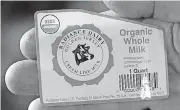  ?? [AP PHOTO] ?? Organic dairy farmer Francis Thicke holds the label for milk produced on his farm in Fairfield, Iowa. Small organic dairy farms with cows freely grazing on verdant pastures are going out of business while large operations with thousands of animals are expanding.