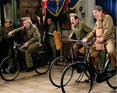  ??  ?? They don’t like it up ’em! Armed with brooms and old swords, Lance-Corporal Jones (left) leads Walker (centre) and Pike as they practise a cavalry charge against invading Germans in the Walmington-onSea church hall . . . on old bicycles