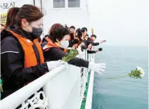  ?? Yonhap ?? Bereaved people who lost family members in the Sewol ferry accident throw flowers into the sea off the country’s southweste­rn Jin Island, Tuesday. The Sewol ferry sank at the location on its way south to Jeju Island on April 16, 2014, claiming 304 lives, mostly high school students on a school excursion.