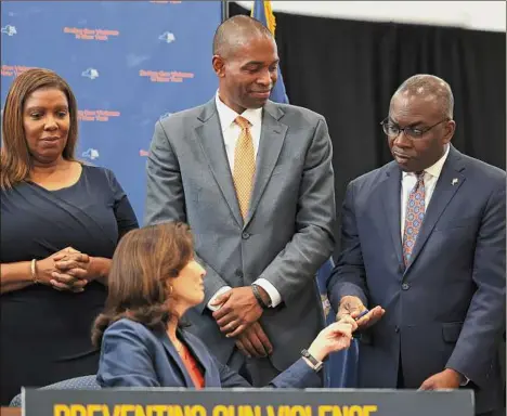  ?? Michael M. Santiago / Getty Images ?? Gov. Kathy Hochul gives a pen to Buffalo Mayor Byron Brown on Monday during a bill-signing ceremony in New York City. Hochul signed a series of gun reform bills that will strengthen gun laws in the state. Passed by lawmakers last week, one restrictio­n includes banning anyone younger than 21 from buying or possessing a semiautoma­tic rifle.