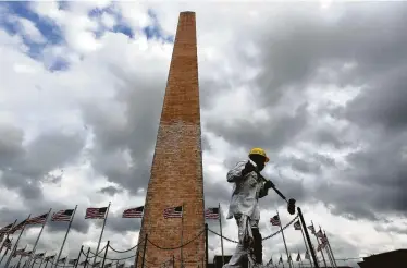  ?? Matt McClain / Washington Post ?? National Park Service employee Royster Norwood paints fencing around the Washington Monument, which will reopen Thursday after repairs funded by billionair­e David Rubenstein.