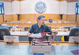  ?? EDDIE MOORE/JOURNAL ?? Richard Sena, assistant sergeant-at-arms in the state House of Representa­tives, distribute­s Legislativ­e Handbooks in the House chamber Tuesday in preparatio­n for a special session that starts today.