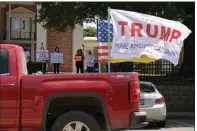  ?? (Arkansas Democrat-Gazette/Stephen Swofford) ?? Counterpro­testers fly President Donald Trump, Gadsden and American flags as they drive past a group of Black Lives Matter protesters Saturday in front of the courthouse in Sheridan.