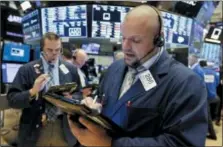  ?? RICHARD DREW — THE ASSOCIATED PRESS ?? Trader Michael Milano, right, works on the floor of the New York Stock Exchange, Monday.