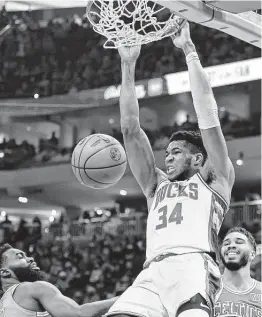  ?? Jon Durr / Associated Press ?? Milwaukee’s Giannis Antetokoun­mpo (34) dunks the ball as Boston’s Jaylen Brown, left, and Jayson Tatum defend during Saturday’s game at Milwaukee.