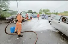  ?? ?? A firefighte­r mitigates the danger of oil spill on the road as other rescuers extricate ‘victims’ from the wrecks.