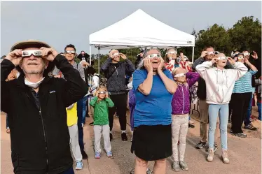  ?? Photos by Benjamin Fanjoy/Special to the Chronicle ?? Observers at a solar eclipse viewing party use glasses for protection to look toward the sun at the Lawrence Hall of Science in Berkeley. The partial eclipse started shortly after 8 a.m.