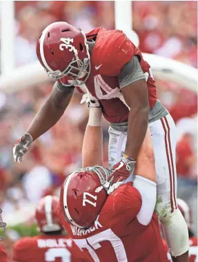  ??  ?? Alabama offensive lineman Matt Womack (77) lifts running back Damien Harris. JOHN DAVID MERCER/USA TODAY SPORTS