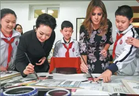  ?? GREG BAKER / REUTERS ?? China’s First Lady Peng Liyuan and US First Lady Melania Trump paint the eyes of panda figures in a calligraph­y class during a visit to Banchang Elementary School in Beijing on Thursday.