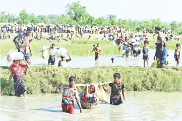  ??  ?? This file photo shows Rohingya refugees carrying a woman over a canal after crossing the Naf River as they flee violence in Myanmar to reach Bangladesh in Palongkhal­i near Ukhia. — AFP photo