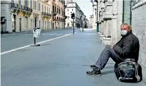  ?? AFP ?? A homeless man sits in a deserted Via del Corso main street in central Rome during the country’s lockdown aimed at stopping the spread of the COVID-19 (new coronaviru­s) pandemic.