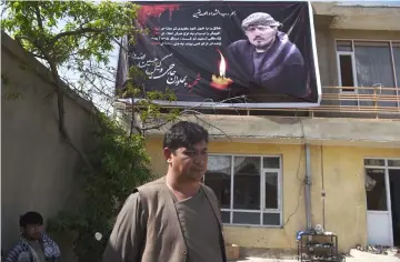  ??  ?? Ghulam, 38, looks on as he stands under a poster with the image of his brother Wakil, one of the 57 victims of a bomb blast, a day after the attack on a voter registrati­on centre, at Wakil’s house in Kabul. — AFP photo