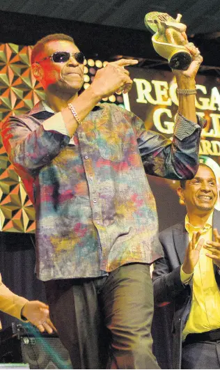  ??  ?? Veteran sound system owner Winston ‘Wee Pow’ Powell of Stone Love holds up his Reggae Gold Awards, which he received earlier this year at the National Indoor Sports Centre.