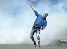  ?? DAR YASIN/ASSOCIATED PRESS ?? A Kashmiri protester throws a rock at Indian policemen in Srinagar, Indian controlled Kashmir, on Wednesday.