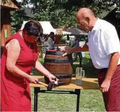  ??  ?? Ursula Schrenner (v.l.) schlägt den Zapfhahn in das Bierfass, während Karl Heinz Höfer mit Bierkrügen zum Zapfen bereit steht.