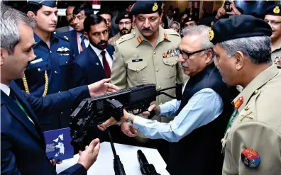  ??  ?? Pakistani President ArifAlvi looks at a weapon that can take shots around corners during a visit to the 10th Internatio­nal Defense Exhibition and Seminar (IDEAS) at the Expo Center in Karachi.