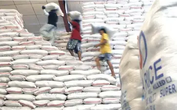  ?? REUTERS ?? Workers are seen lifting heavy sacks of rice at a National Food Authority (NFA) warehouse outside of Manila.